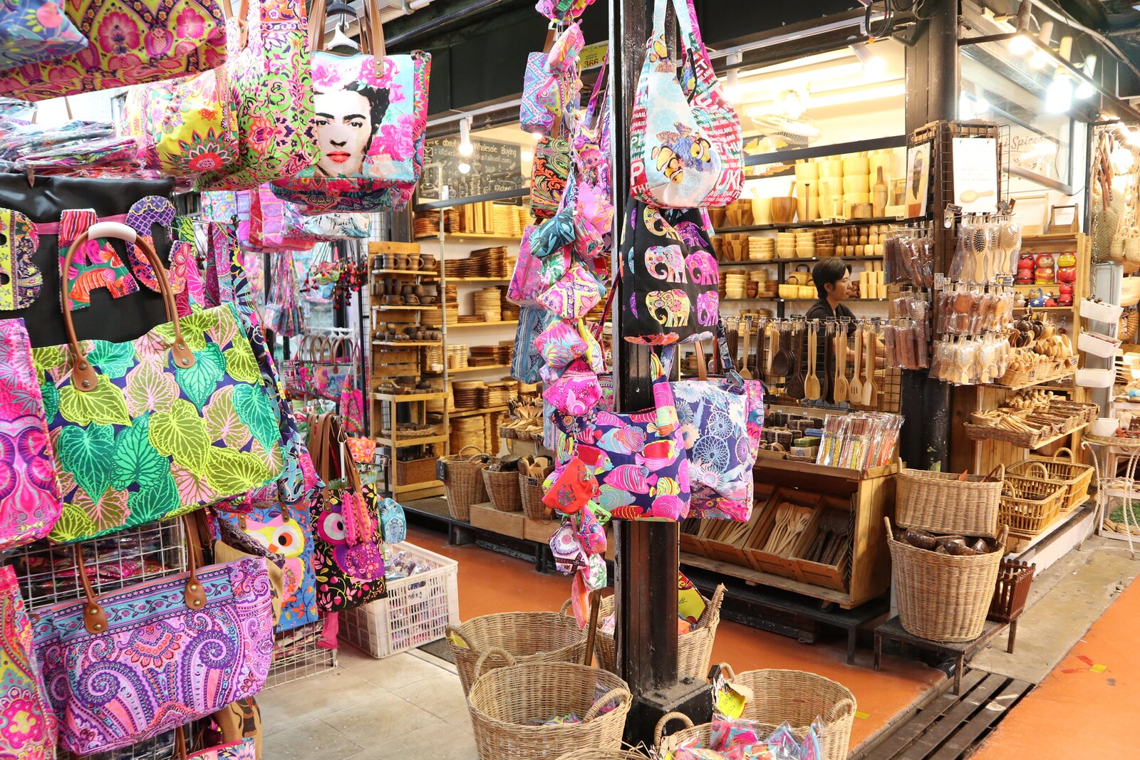 Adjacent Chatuchak stalls displaying colorful textile bags and wooden objects