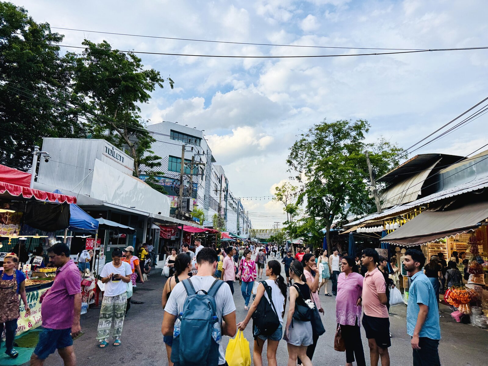 夕方の照明がつき始めた通路で、スポーツジャージが並ぶ売場の前を人々が歩く