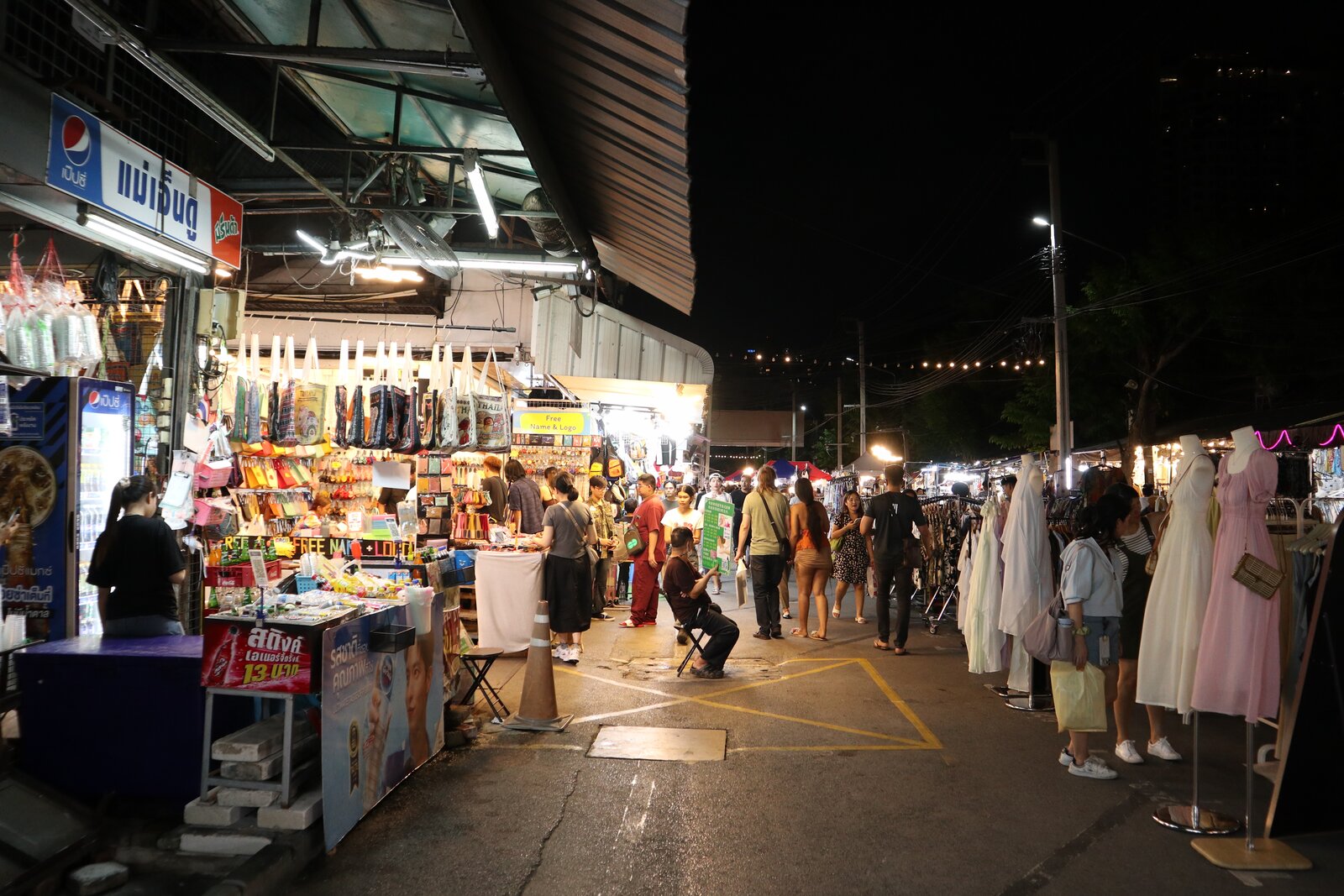 夜の市場通りを歩く人々と、左右に明るく照らされた店舗