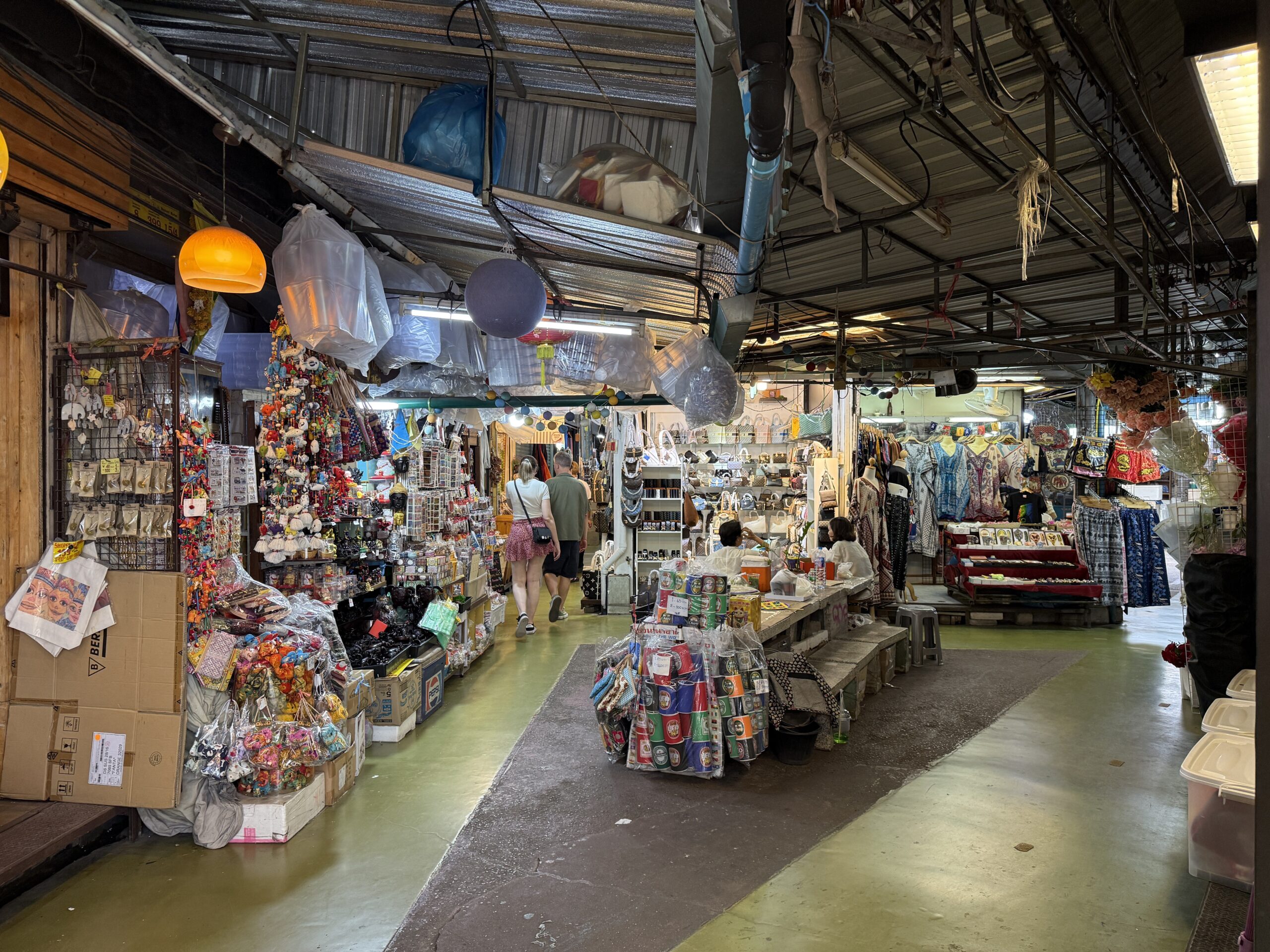 Two visitors walking into a branching aisle lined with market stalls