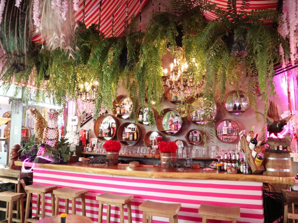 The Secret bar counter surrounded by hanging plants and chandeliers
