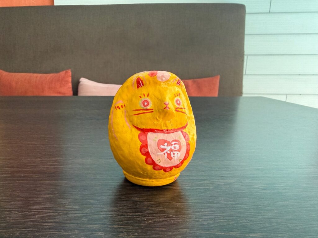 Yellow cat Daruma art with the Japanese character for good fortune