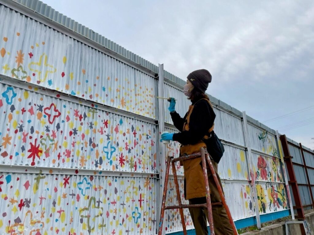 Kotori/KTR painting a mural on an exterior wall