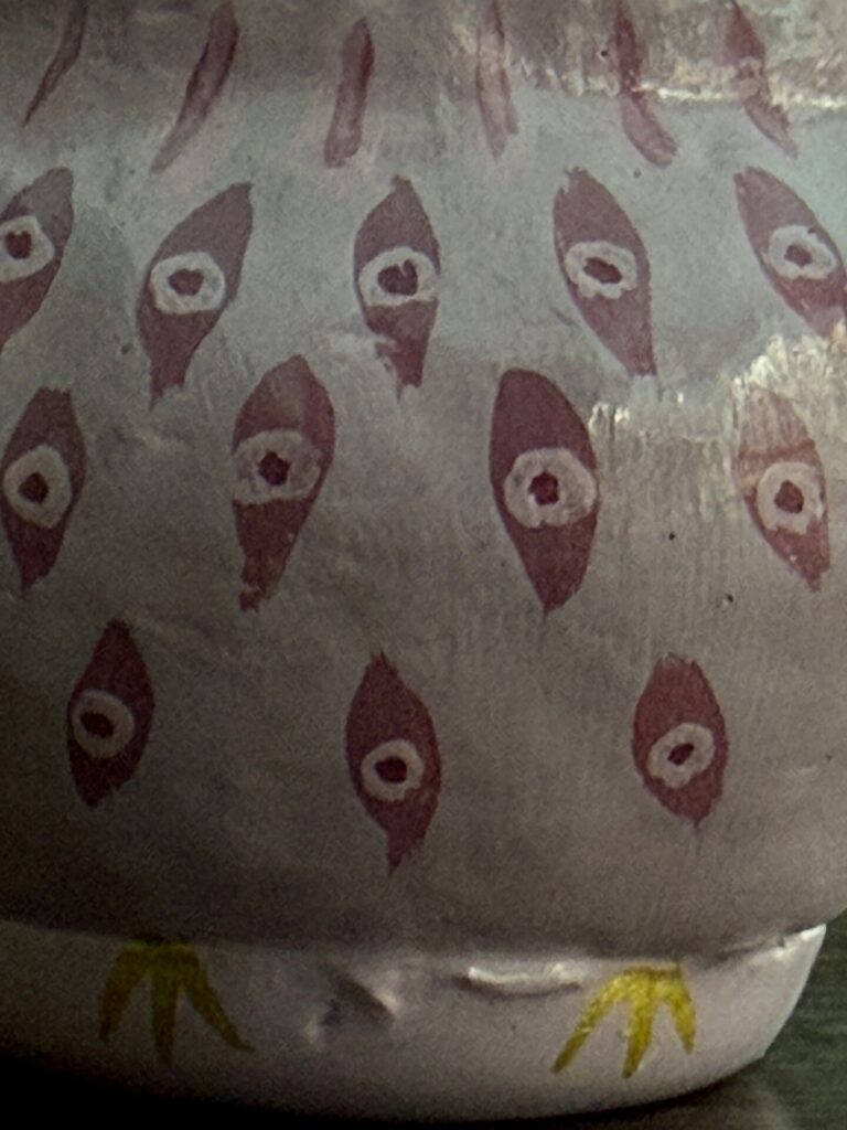 Close-up of repeated eye motifs painted on a Daruma art piece