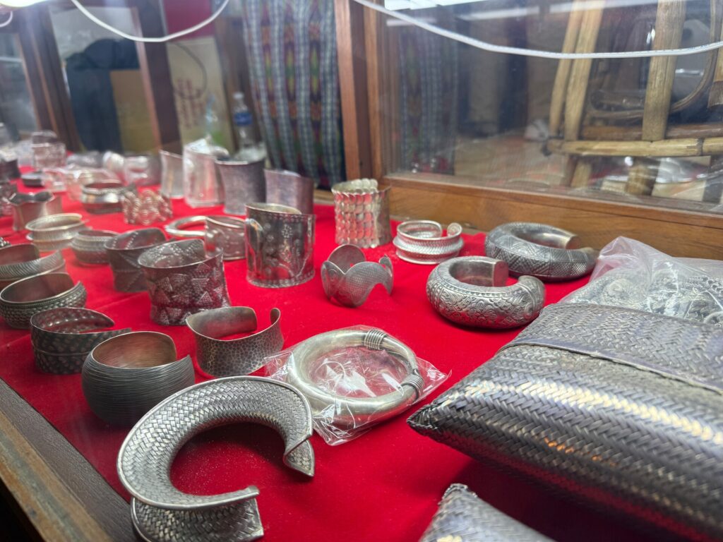 Engraved Karen silver bracelets and cuffs on a red display